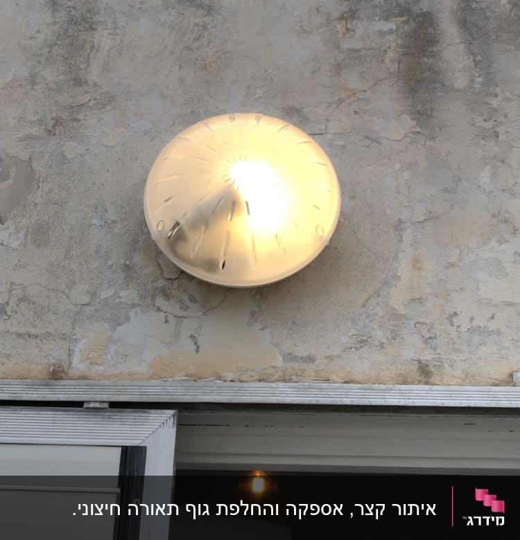 מנורת קיר עגולה דולקת על קיר חיצוני